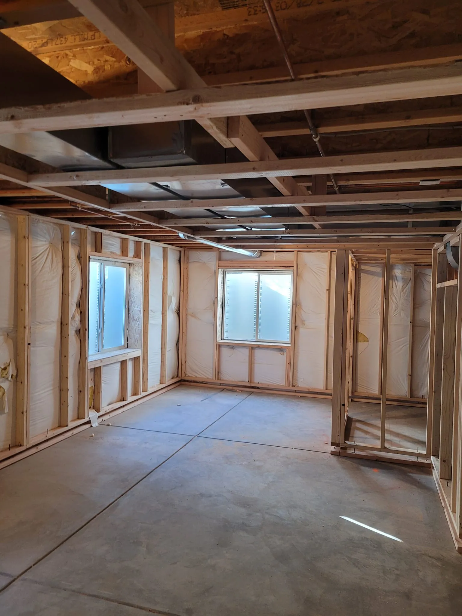 basement-framing-1 Basement Framing,  Great Dane Construction, Front Range, CO: Unfinished room with wooden framing, uninsulated walls, and two windows. Concrete floor is visible.