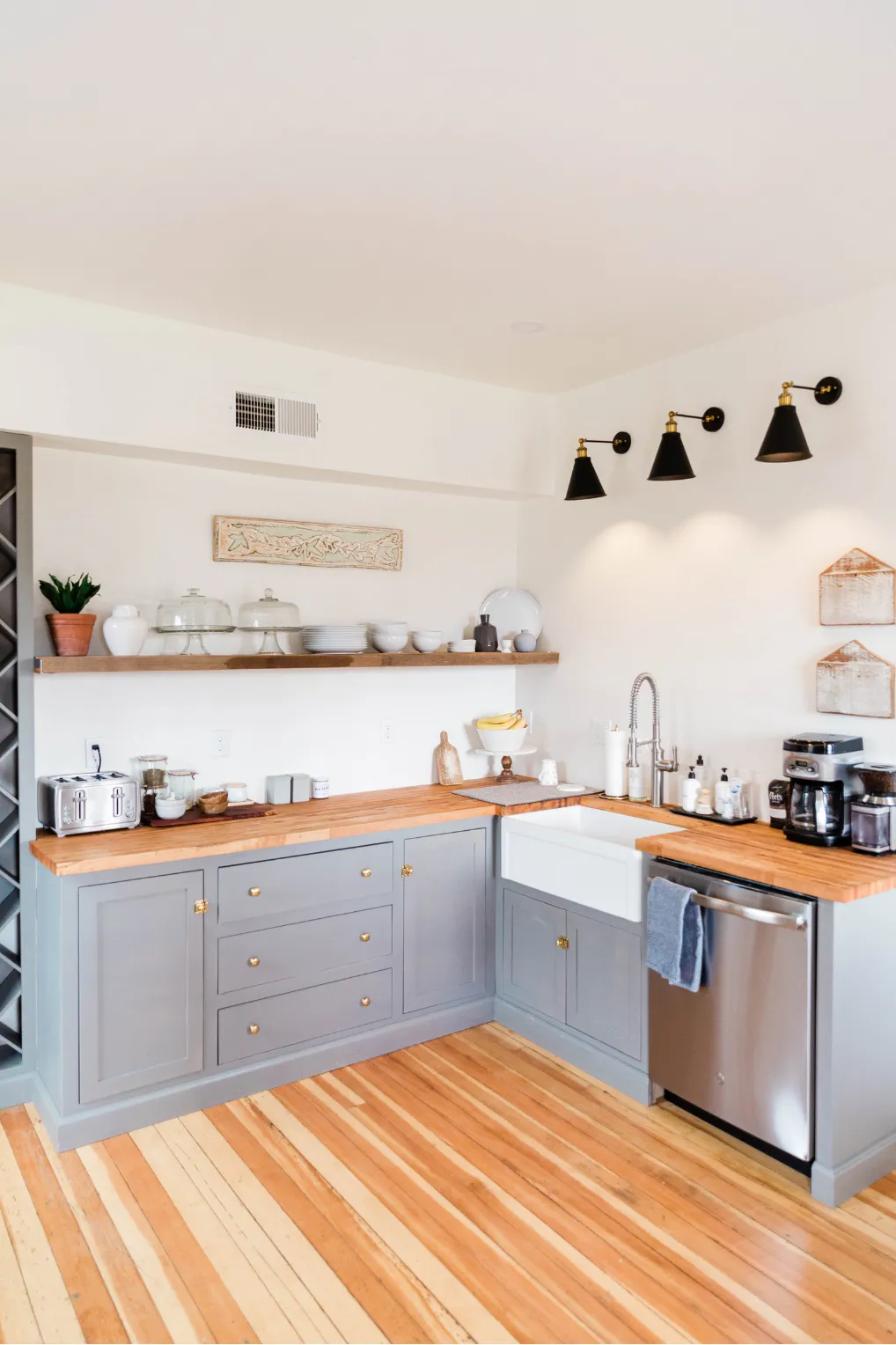 kitchen-remodeling-2 bright kitchen with gray cabinets, wooden countertops, farmhouse sink, and modern black wall lights. example of kitchen remodeling service