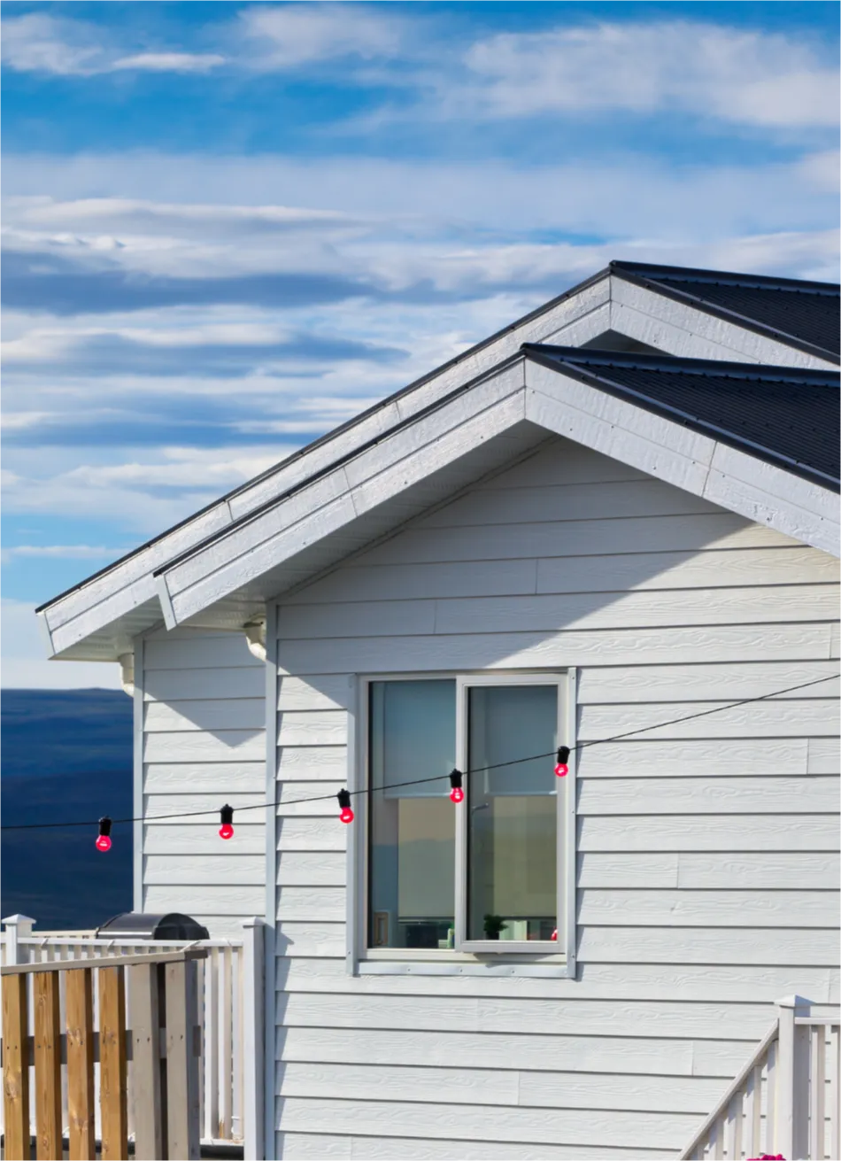 siding-repairs-1 White house with string of red lights against a cloudy blue sky backdrop showing siding repairs